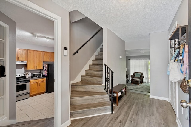 507 NW 39th Rd Unit 154, Gainesville, FL 32607 - foyer featuring a textured ceiling, stairway, and light wood-style flooring