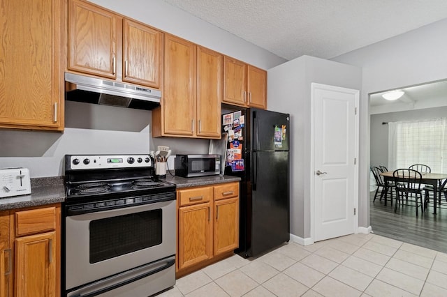 507 NW 39th Rd Unit 154, Gainesville, FL 32607 - kitchen with stainless steel appliances, under cabinet range hood, dark countertops, light tile patterned floors, and brown cabinets