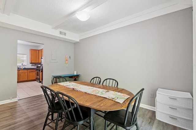 507 NW 39th Rd Unit 154, Gainesville, FL 32607 - dining area with light wood finished floors, beam ceiling, a textured ceiling, and baseboards