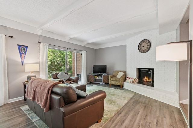 507 NW 39th Rd Unit 154, Gainesville, FL 32607 - living room with a fireplace, beamed ceiling, a textured ceiling, wood finished floors, and baseboards
