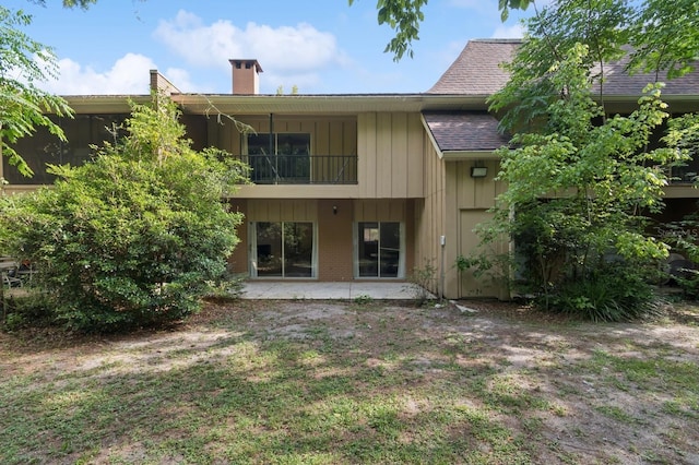 507 NW 39th Rd Unit 154, Gainesville, FL 32607 - rear view of house with a balcony, a shingled roof, board and batten siding, a chimney, and a patio area