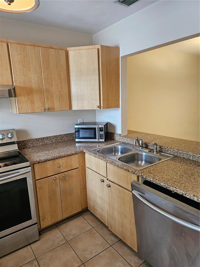 4007 SW 26th Ter Unit B, Gainesville, FL 32608 - kitchen featuring stainless steel appliances, a sink, light brown cabinetry, light tile patterned floors, and dark countertops