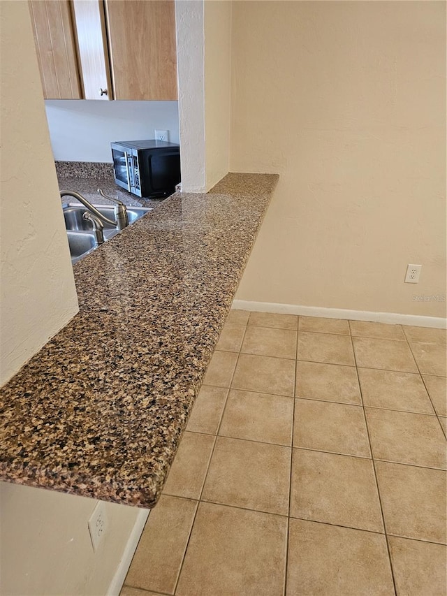 4007 SW 26th Ter Unit B, Gainesville, FL 32608 - kitchen with dark countertops, a sink, tile patterned floors, and baseboards