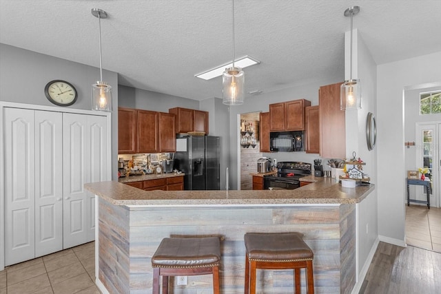 13365 Chesapeake Pl, Spring Hill, FL 34609 - kitchen with black appliances, brown cabinets, light countertops, a peninsula, and decorative light fixtures
