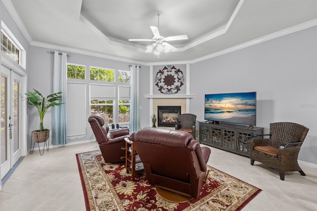 923 SW 85th Way, Gainesville, FL 32607 - tiled living room with a tray ceiling, a tiled fireplace, ceiling fan, crown molding, and baseboards