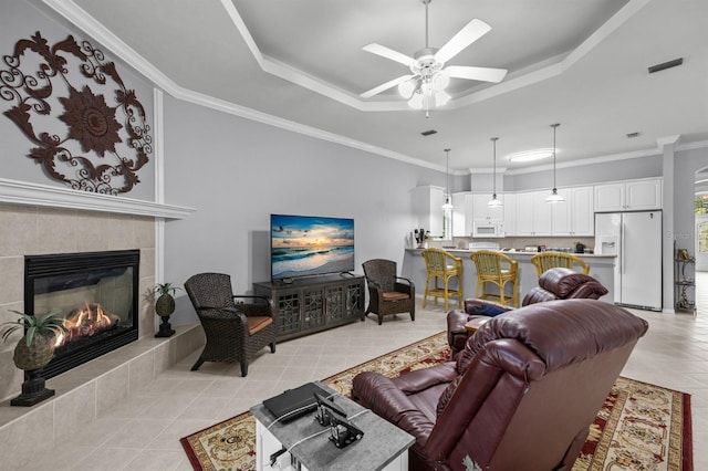 923 SW 85th Way, Gainesville, FL 32607 - living room with a tray ceiling, light tile patterned floors, ceiling fan, a tile fireplace, and ornamental molding