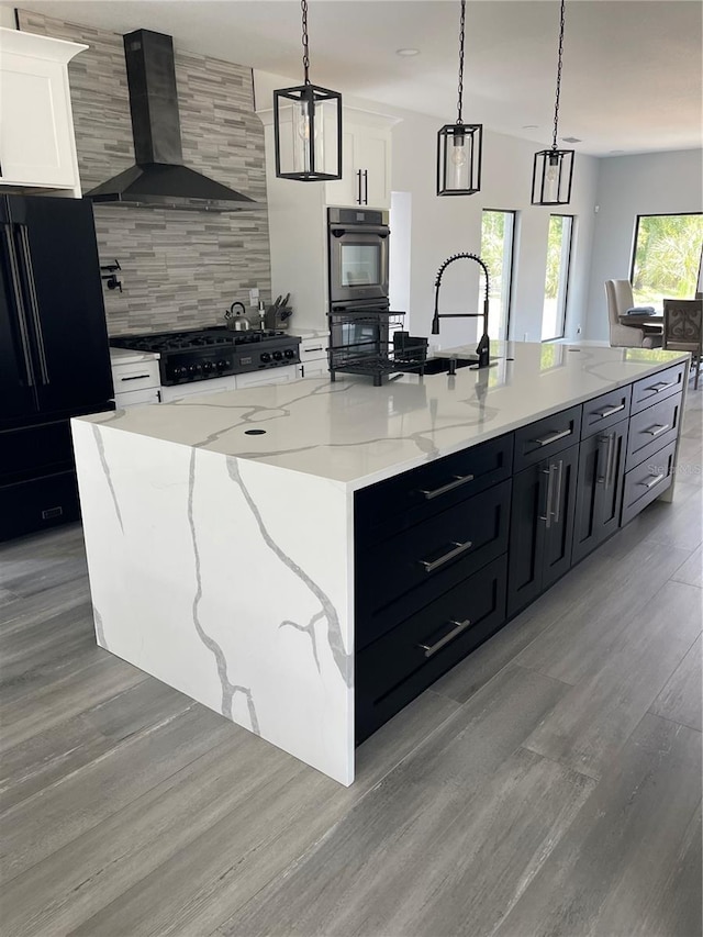 2518 Sunset Ln, Lutz, FL 33559 - kitchen featuring wall chimney exhaust hood, black appliances, backsplash, a large island with sink, and light wood-type flooring