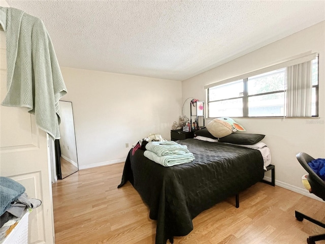 2811 SW Archer Rd Unit T164, Gainesville, FL 32608 - bedroom featuring light wood-type flooring, a textured ceiling, and baseboards