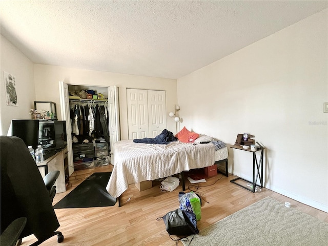 2811 SW Archer Rd Unit T164, Gainesville, FL 32608 - bedroom with two closets, wood finished floors, a desk, and a textured ceiling
