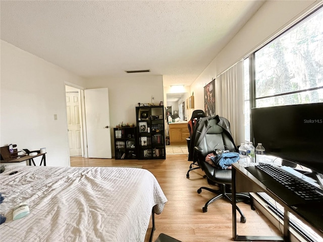 2811 SW Archer Rd Unit T164, Gainesville, FL 32608 - bedroom with wood finished floors, a textured ceiling, ensuite bathroom, and an office area