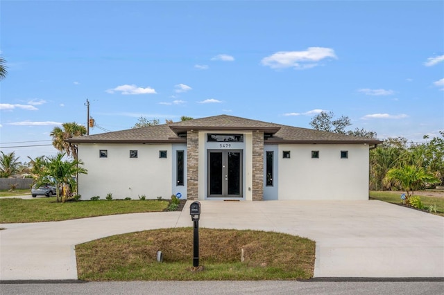 5479 S Biscayne Dr, North Port, FL 34287 - prairie-style house featuring french doors, stucco siding, curved driveway, and stone siding