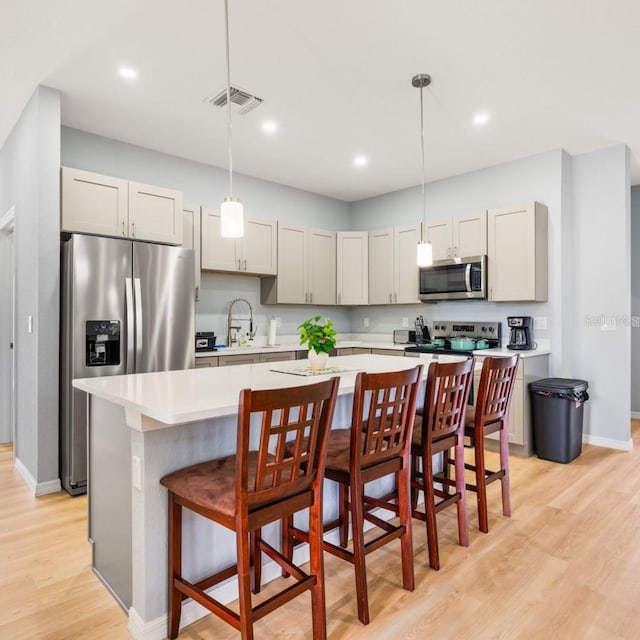 5479 S Biscayne Dr, North Port, FL 34287 - kitchen featuring appliances with stainless steel finishes, light countertops, light wood finished floors, a center island, and a sink
