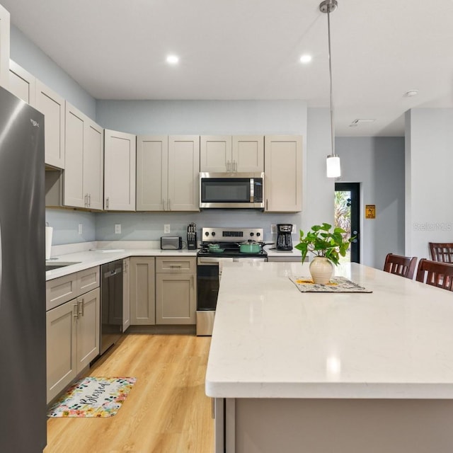 5479 S Biscayne Dr, North Port, FL 34287 - kitchen featuring stainless steel appliances, pendant lighting, recessed lighting, light wood finished floors, and a center island