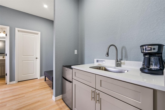 5479 S Biscayne Dr, North Port, FL 34287 - kitchen featuring a sink, light wood-style floors, baseboards, light stone counters, and a textured wall