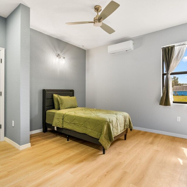 5479 S Biscayne Dr, North Port, FL 34287 - bedroom with a wall mounted AC, light wood finished floors, ceiling fan, and baseboards
