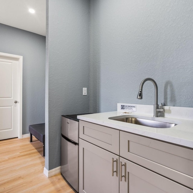 5479 S Biscayne Dr, North Port, FL 34287 - kitchen with a sink, light wood-style flooring, a textured wall, light stone counters, and baseboards
