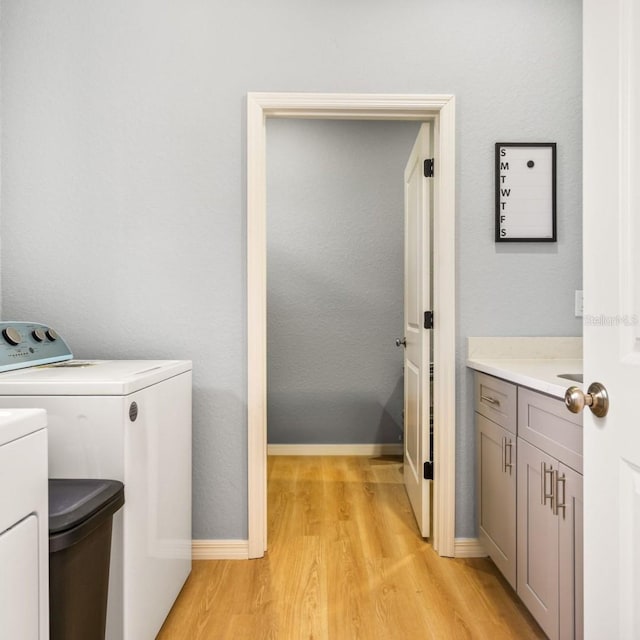 5479 S Biscayne Dr, North Port, FL 34287 - laundry room featuring washing machine and clothes dryer, light wood-style floors, baseboards, and cabinet space