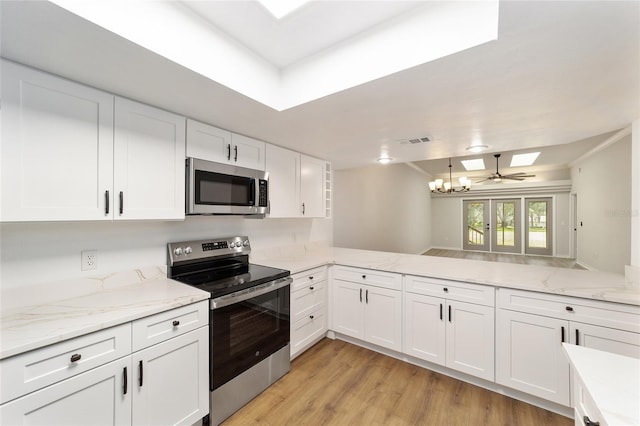 6245 NW 106th Pl Unit 6245, Alachua, FL 32615 - kitchen featuring stainless steel appliances, a skylight, white cabinets, light wood-style flooring, and a chandelier