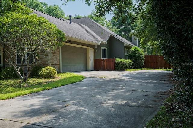 5119 NW 57th St, Gainesville, FL 32653 - view of side of home with a shingled roof, driveway, an attached garage, stone siding, and stucco siding