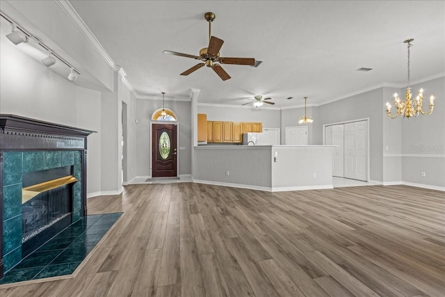 11737 Creek Dr, Alachua, FL 32615 - unfurnished living room featuring a tiled fireplace, wood finished floors, a ceiling fan, track lighting, and ornamental molding
