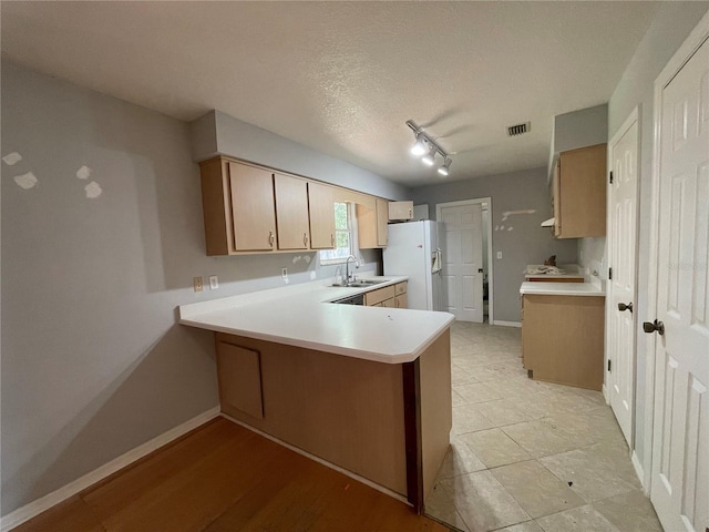395 SW Grove St, Keystone Heights, FL 32656 - kitchen with white refrigerator with ice dispenser, a sink, light countertops, a peninsula, and baseboards