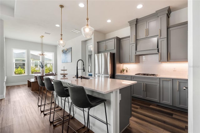 3225 SW 120th Ter, Gainesville, FL 32608 - kitchen with gray cabinetry, appliances with stainless steel finishes, a kitchen island with sink, dark wood-type flooring, and tasteful backsplash