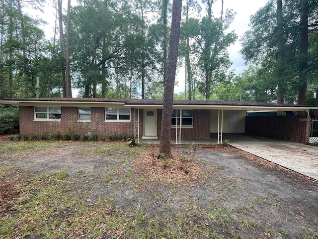 1702 NE 15th Ter, Gainesville, FL 32609 - ranch-style house with driveway, brick siding, an attached carport, and view of scattered trees