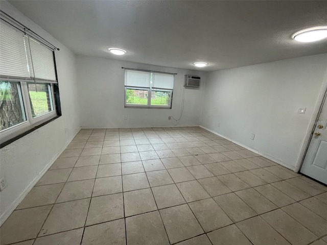 1702 NE 15th Ter, Gainesville, FL 32609 - unfurnished room with an AC wall unit, light tile patterned floors, and baseboards