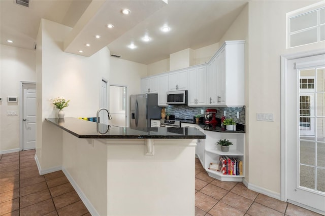 10303 SW 21st Ave, Gainesville, FL 32607 - kitchen with appliances with stainless steel finishes, light tile patterned flooring, decorative backsplash, white cabinets, and a kitchen breakfast bar