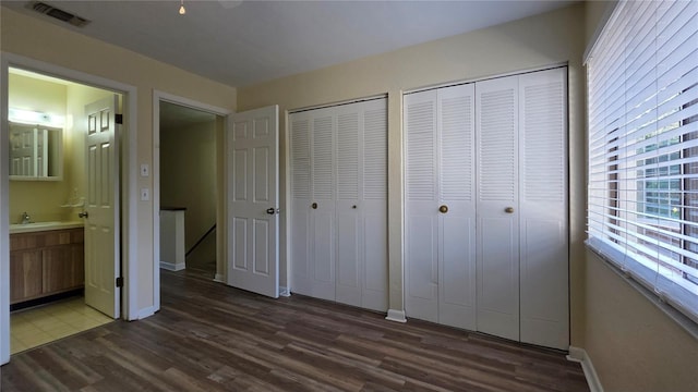 2635 SW 35th Pl Unit 1705, Gainesville, FL 32608 - unfurnished bedroom with multiple closets, dark wood-style floors, connected bathroom, and baseboards