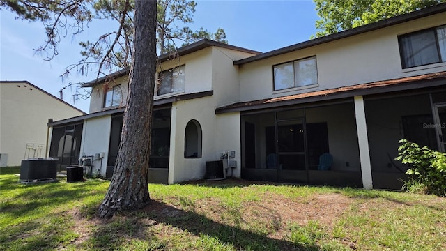 2635 SW 35th Pl Unit 1705, Gainesville, FL 32608 - rear view of property featuring a sunroom, central air condition unit, stucco siding, and a lawn