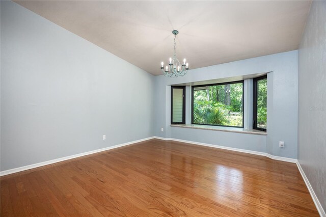 6425 NW 97th Ct, Gainesville, FL 32653 - spare room with a chandelier, wood finished floors, and baseboards