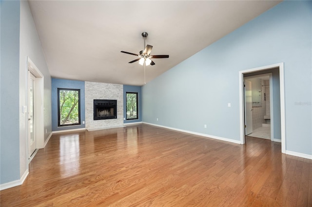 6425 NW 97th Ct, Gainesville, FL 32653 - unfurnished living room featuring lofted ceiling, ceiling fan, wood finished floors, a stone fireplace, and baseboards