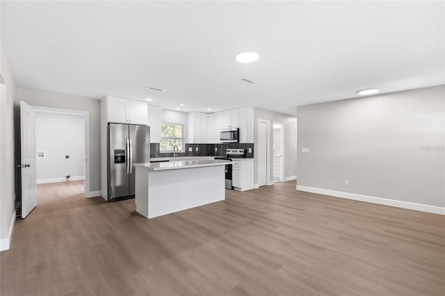 3237 NW 30th Ave, Gainesville, FL 32605 - kitchen with stainless steel appliances, a center island, baseboards, wood finished floors, and recessed lighting