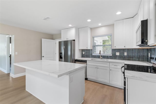3237 NW 30th Ave, Gainesville, FL 32605 - kitchen featuring appliances with stainless steel finishes, a sink, a kitchen island, light wood-style floors, and tasteful backsplash