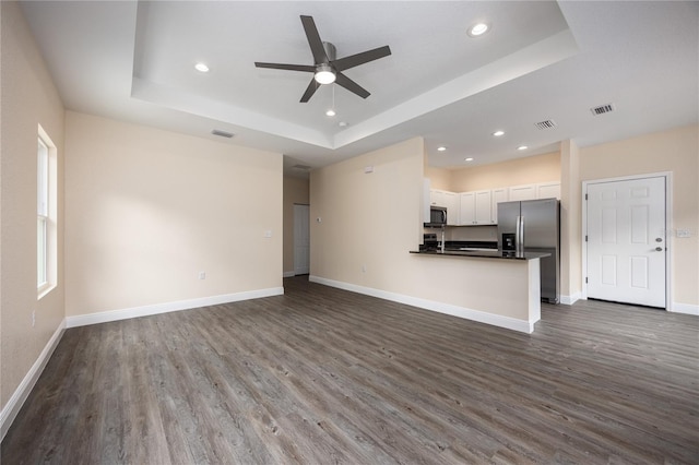 15217 NW 134th Ter, Alachua, FL 32615 - unfurnished living room with a raised ceiling, ceiling fan, recessed lighting, dark wood-style floors, and baseboards