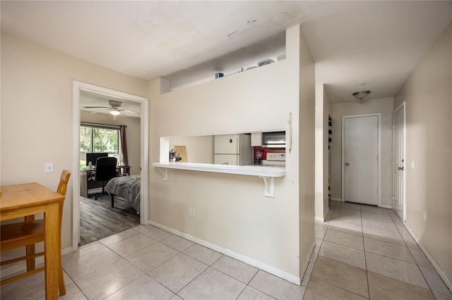 3921 SW 34th St Unit 106, Gainesville, FL 32608 - kitchen featuring white appliances, light tile patterned flooring, a breakfast bar, and a ceiling fan