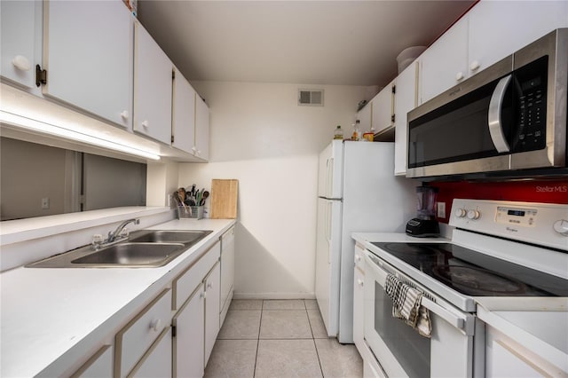3921 SW 34th St Unit 106, Gainesville, FL 32608 - kitchen featuring white range with electric stovetop, stainless steel microwave, white cabinetry, light countertops, and light tile patterned floors