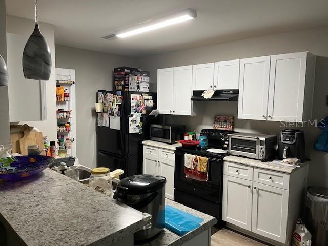 633 SW Magnolia Ave, Keystone Heights, FL 32656 - kitchen featuring black appliances, under cabinet range hood, white cabinetry, and a peninsula