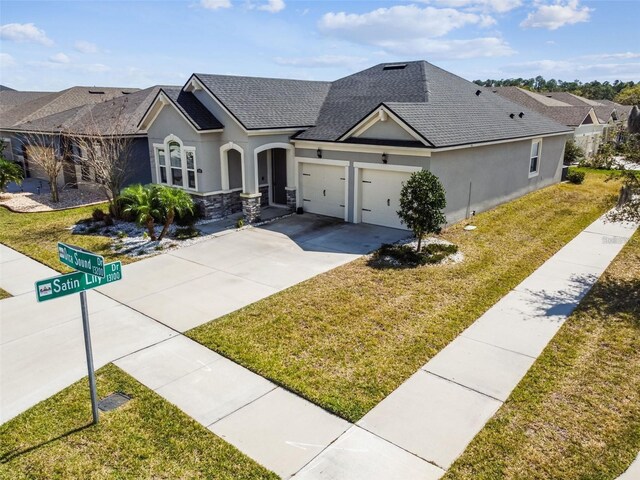 13201 Orca Sound Dr, Riverview, FL 33579 - view of front of home with stucco siding, a shingled roof, an attached garage, a front yard, and driveway