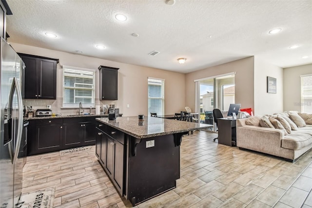 13201 Orca Sound Dr, Riverview, FL 33579 - kitchen with open floor plan, a sink, a center island, a breakfast bar, and dark stone countertops