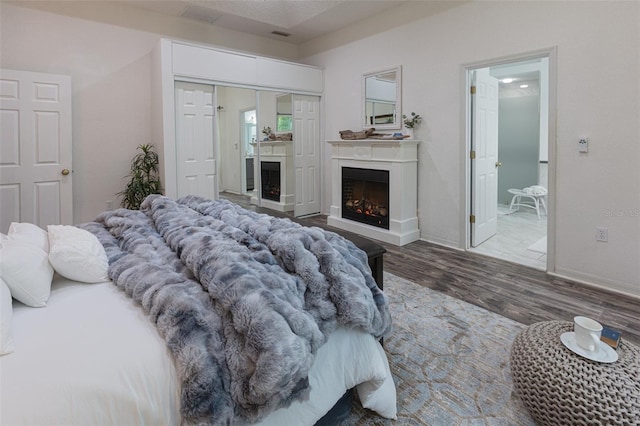 2072 SW 66th Dr, Gainesville, FL 32607 - bedroom featuring wood finished floors, a warm lit fireplace, and ensuite bath