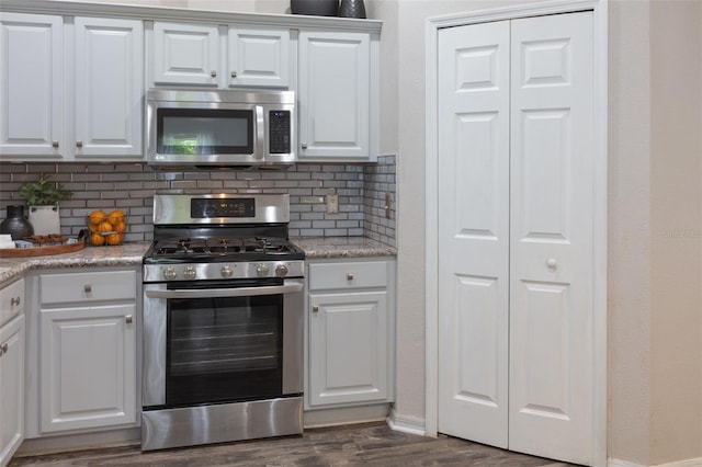 2072 SW 66th Dr, Gainesville, FL 32607 - kitchen featuring appliances with stainless steel finishes, decorative backsplash, dark wood-style flooring, and white cabinets