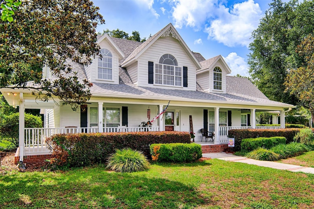 24203 NW 94th Ave, Alachua, FL 32615 - view of front of home with a porch, a front yard, and roof with shingles