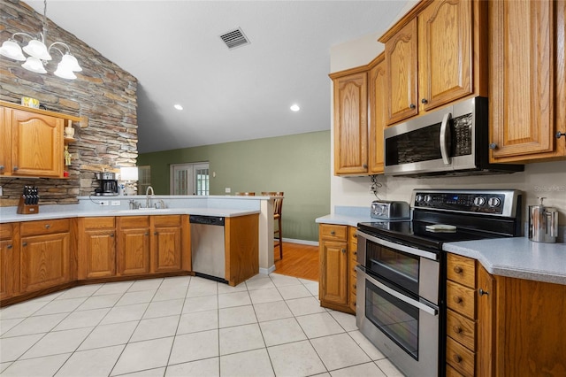 1827 SW Shiloh St, Fort White, FL 32038 - kitchen with stainless steel appliances, a peninsula, brown cabinetry, light countertops, and recessed lighting