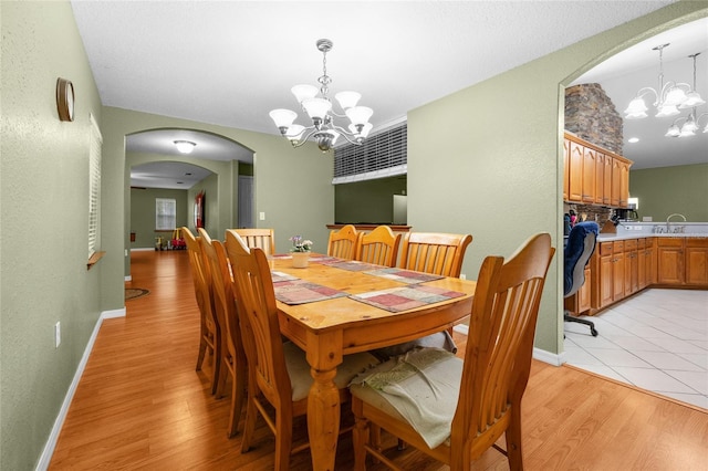 1827 SW Shiloh St, Fort White, FL 32038 - dining area with a chandelier, arched walkways, light wood-type flooring, and baseboards
