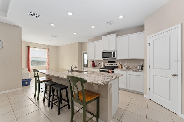 8123 SW 57th Ct, Ocala, FL 34476 - kitchen featuring appliances with stainless steel finishes, a center island with sink, a kitchen bar, light tile patterned floors, and recessed lighting