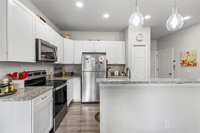 14214 NW 154th Pl, Alachua, FL 32615 - kitchen featuring stainless steel appliances, white cabinets, wood finished floors, light stone counters, and decorative light fixtures