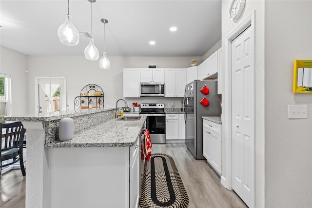14214 NW 154th Pl, Alachua, FL 32615 - kitchen with stainless steel appliances, a sink, light wood finished floors, a breakfast bar area, and white cabinets