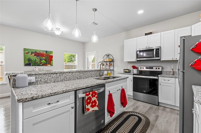 14214 NW 154th Pl, Alachua, FL 32615 - kitchen with stainless steel appliances, a sink, light wood-style flooring, white cabinets, and recessed lighting